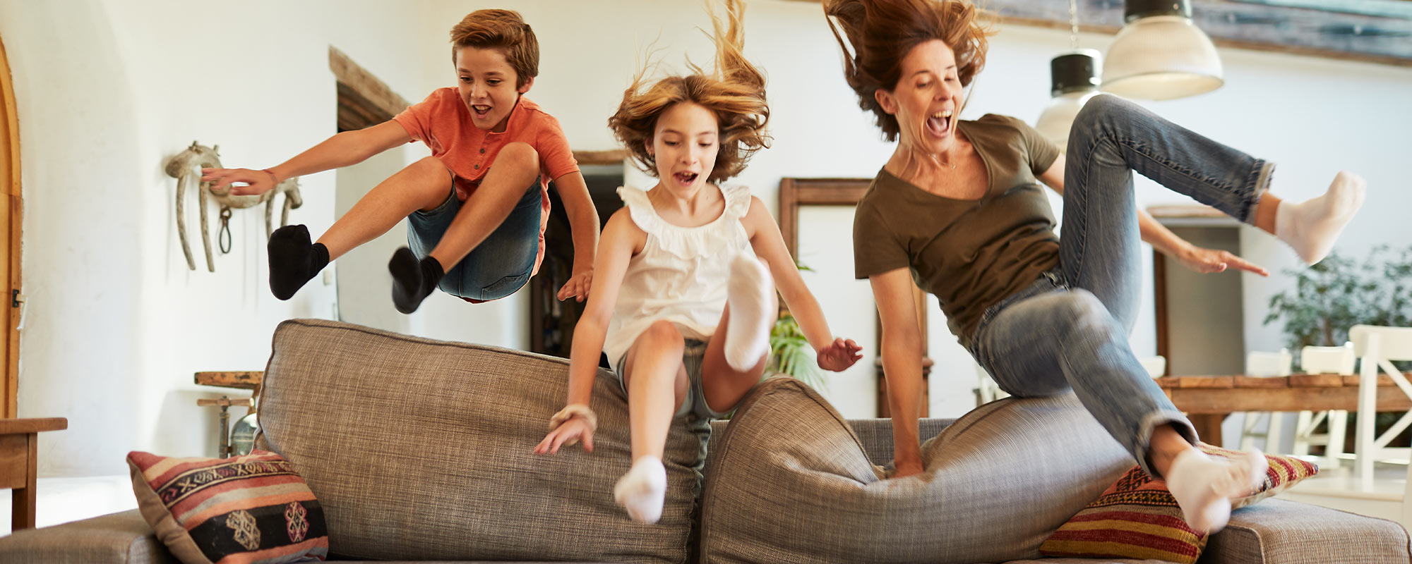 A family excitedly jumping onto a couch